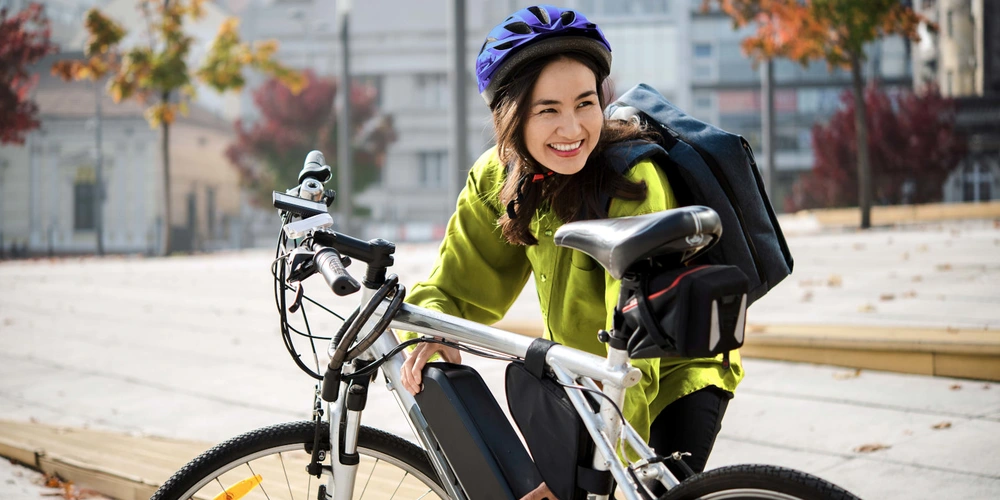 linexo Magazin Radfahrerin setzt einen Akku in ihr E-Bike ein bei herbstlichen Ambiente